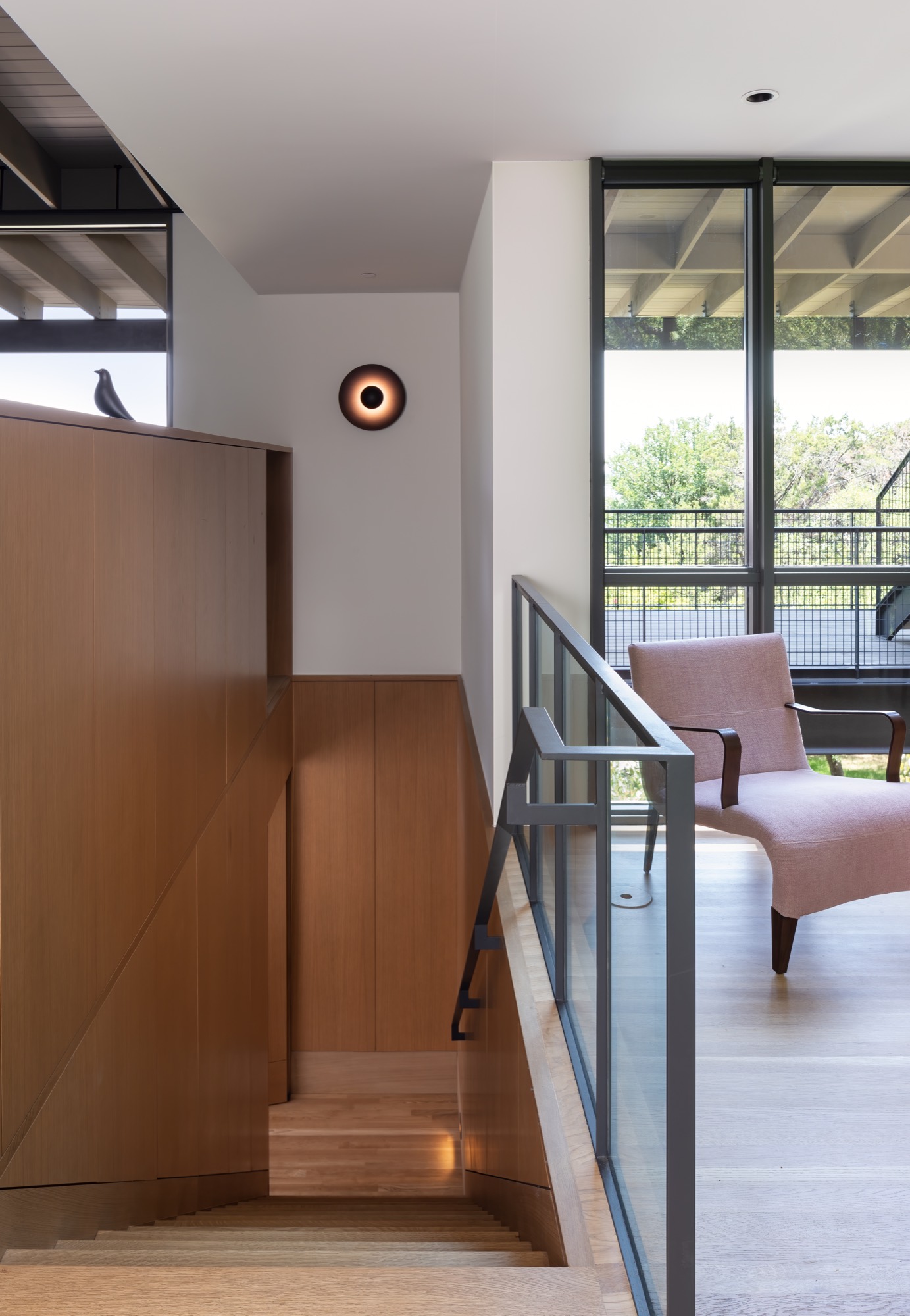 White oak staircase with custom railing descending from the main entry of a modern Austin house