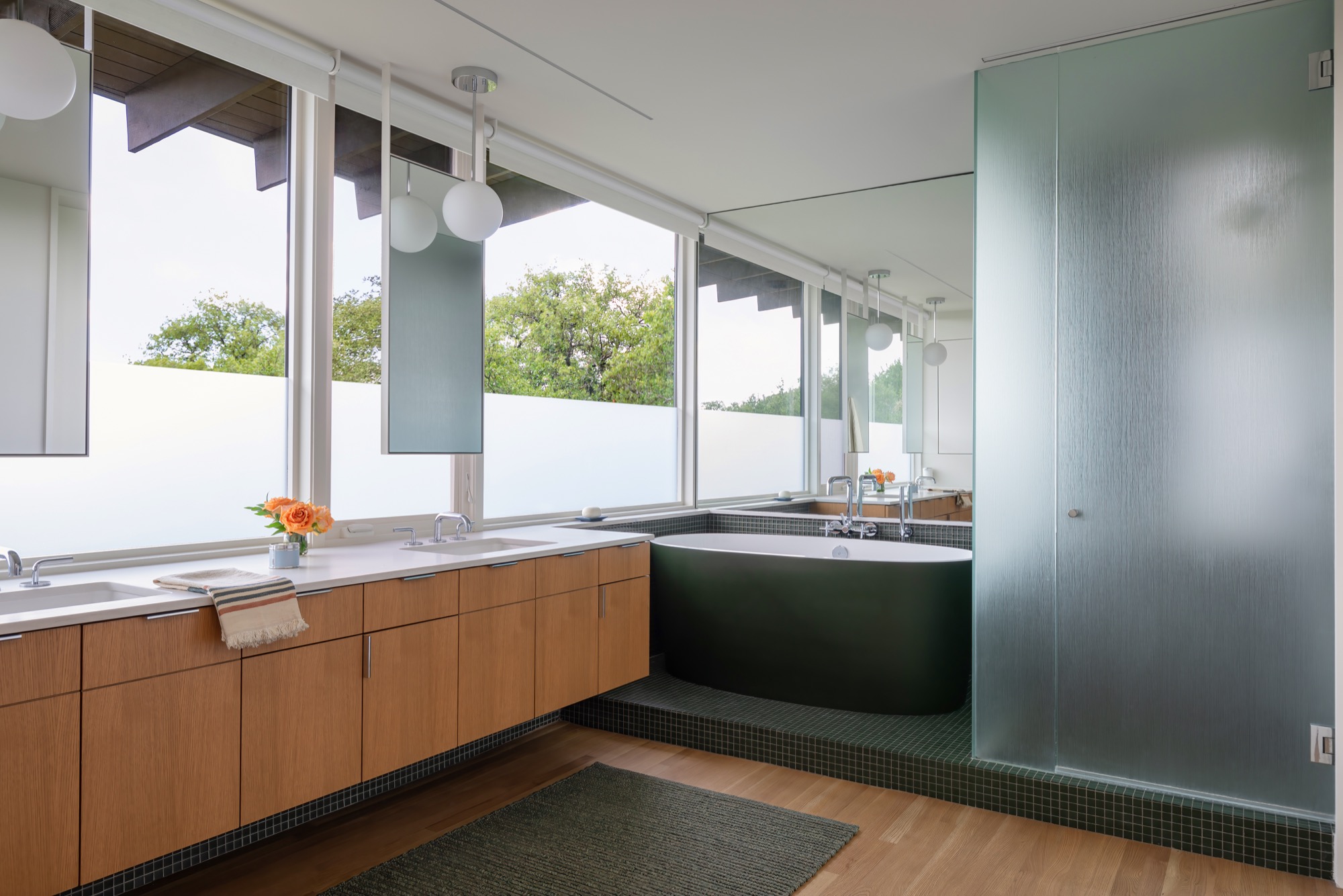 Bathroom of a modern Austin house with a soaking tub, double vanity, and white oak cabinetry
