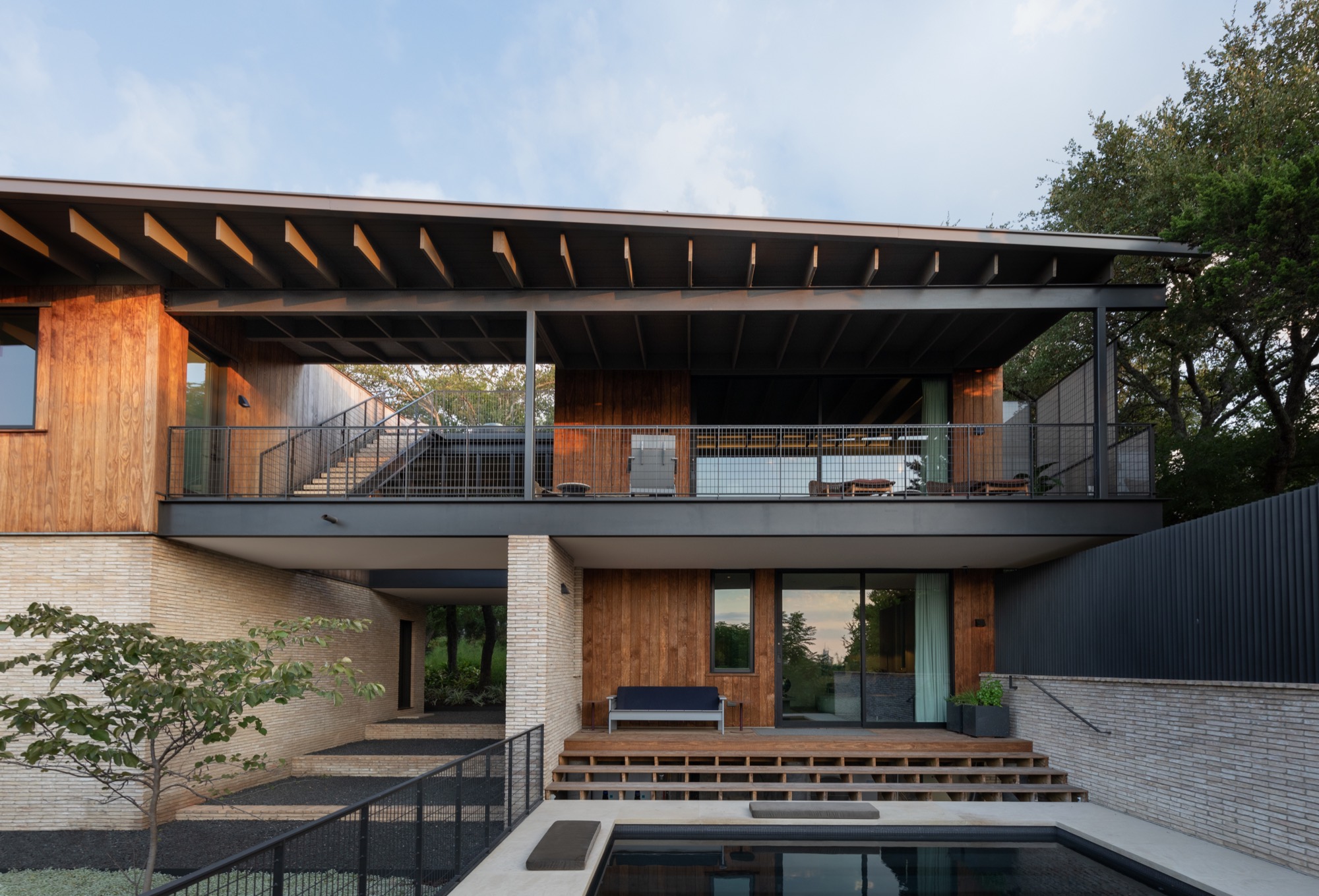 Rear view of a modern Austin house with breezeway, pool, and elevated terrace