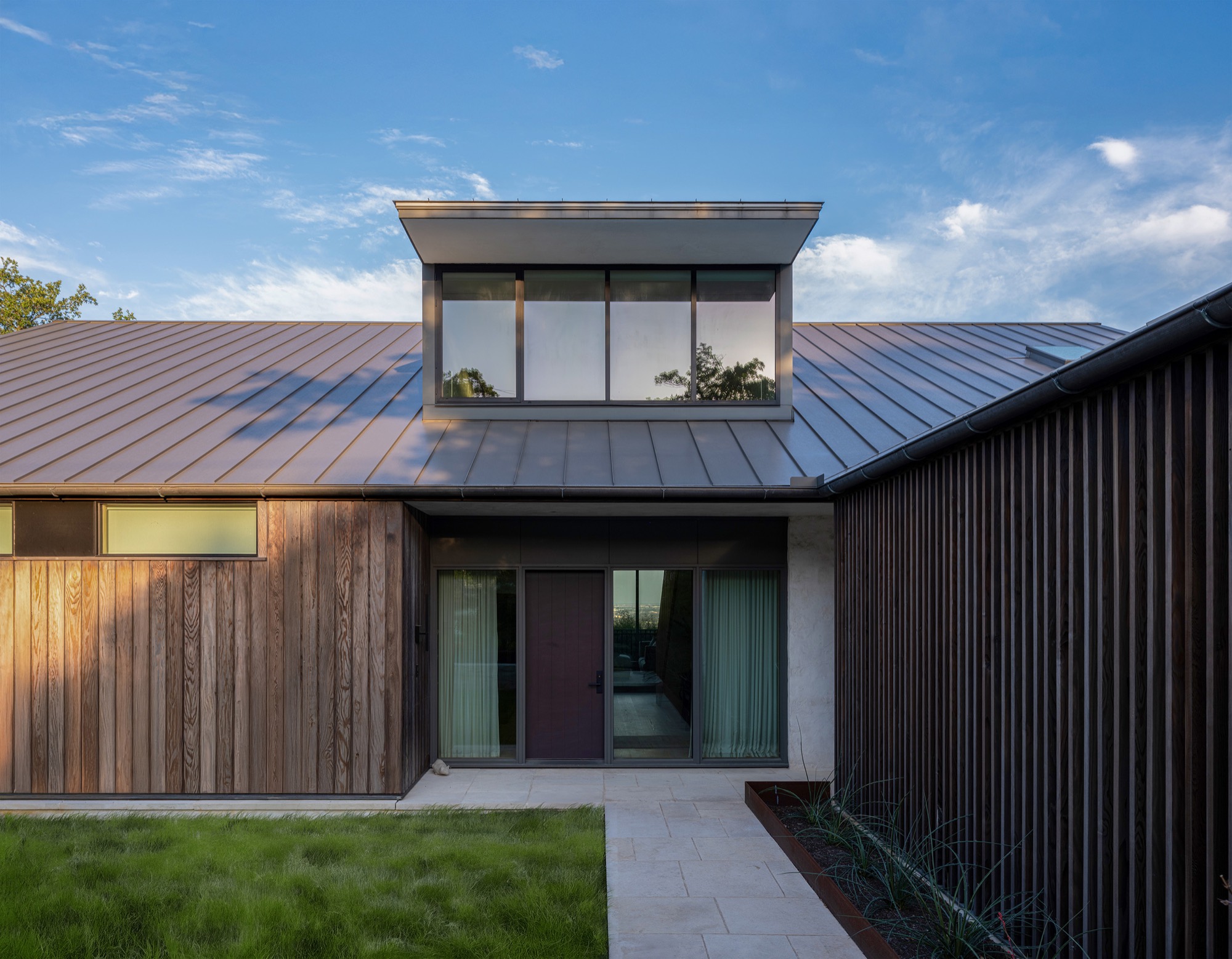 Modern bridge house in Austin with elevated dining volume connecting two structures over courtyard